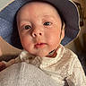 baby, child, face, hat, blue_hat, indoor, person, skin, eyebrows, eyes, clothing, infant, curious, portrait, headwear, closeup, young, cute, cheeks, expression