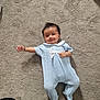 baby, infant, carpet, blue_outfit, knitwear, smiling, lying_down, white_bow, one_arm_outstretched, cheeky_smile, soft_texture, indoor, child, cute, happy, person, footed_pajamas, short_hair, skin, cozy