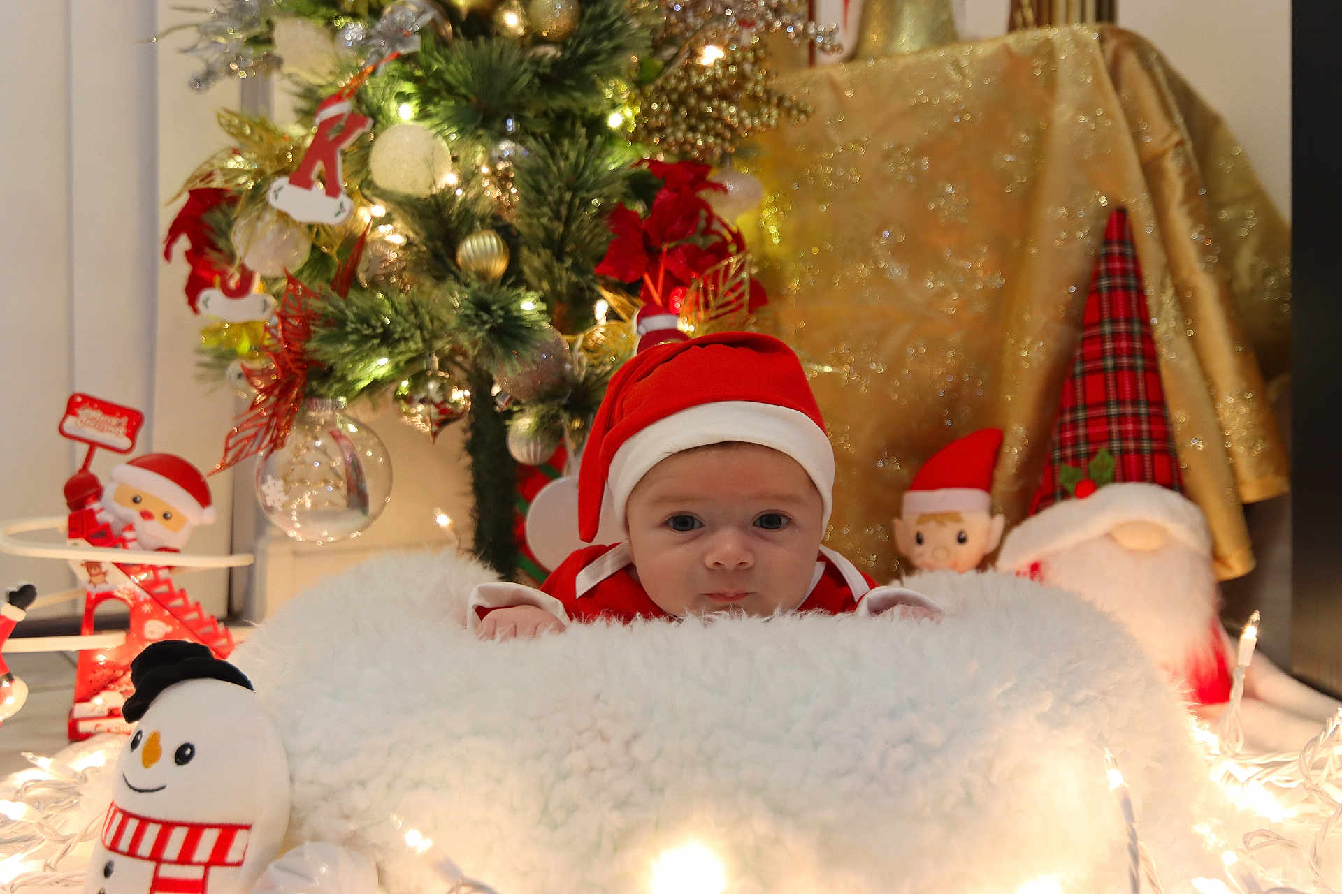 Alexander is registered to the contest to win money with this photo: baby, christmas, holiday, santa_hat, plush, snowman, tree, decorations, lights, festive, blanket, indoors, cute, red, white, face, toy, seasonal, smile, child