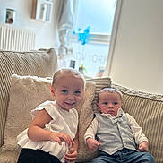 Zelyana participe au concours pour gagner de l'argent avec cette photo : child, toddler, baby, couch, pillow, smiling, curious, white_top, black_pants, vest, jeans, sneakers, indoor, window, natural_light, plush, cozy, furniture, person, portrait