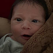 Samuel is registered to the contest to win money with this photo: baby, newborn, infant, face, eyes, blanket, onesie, close_up, portrait, cozy, brown_blanket, hair, mouth, nose, skin, indoors, bedding, sleepy, gaze, soft_texture