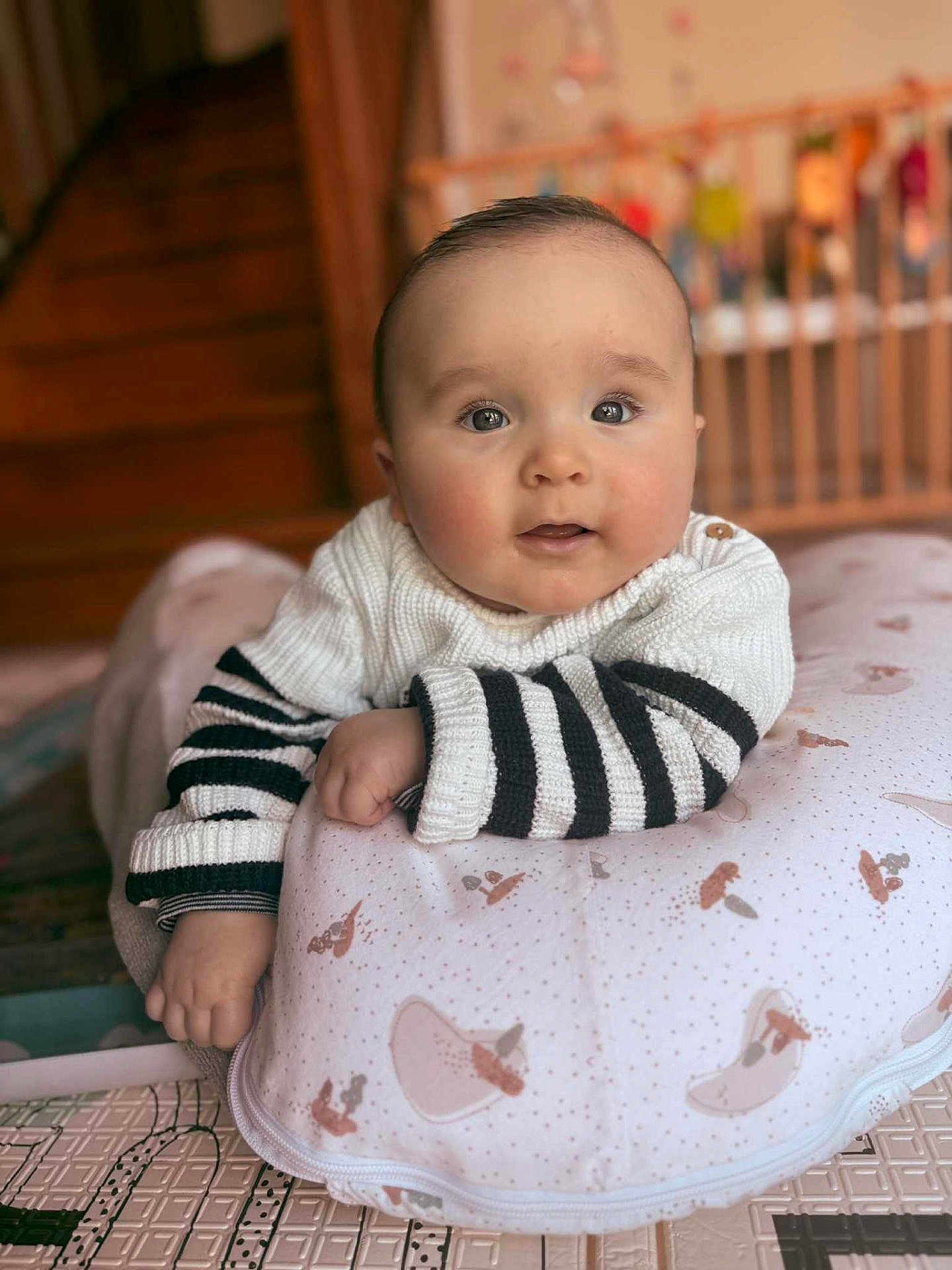 Alix a rejoint le concours — aidez-le/la à gagner de superbes lots ! baby, infant, child, face, eyes, sweater, striped_clothing, pillow, patterned_pillow, hand, arm, soft_lighting, indoors, wooden_stairs, crib, blurred_background, cozy, cute, portrait, lying_down