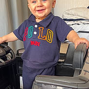Keylan a rejoint le concours — aidez-le/la à gagner de superbes lots ! toddler, child, smiling, toy_car, indoor, clothing, shorts, shirt, happy, blue_eyes, barefoot, necklace, bedroom, curtains, furniture, person, portrait, standing, play, cute