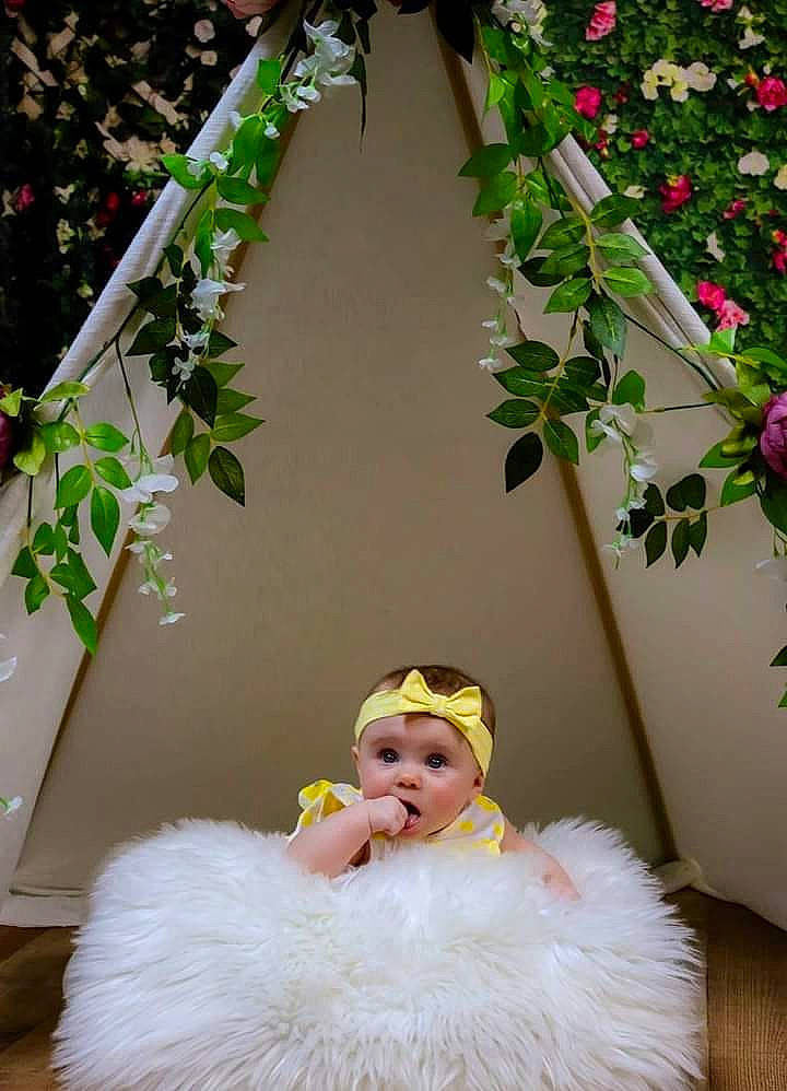 Adilynn is registered to the contest to win money with this photo: baby, child, flower, fur, headwear, person, petal, photography, pink, plant, room, surprise, textile, white