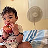 toddler, child, apple, bite, bed, blanket, indoor, person, cute, happy, clothing, bracelet, fan, furniture, home, portrait, sitting, young_child, face, playful