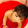 toddler, child, baby, face, curly_hair, red_tub, rattle, bath_time, indoors, skin, looking_up, expression, cute, small_person, playful, arm, necklace, soft_light, close_up, water_toy