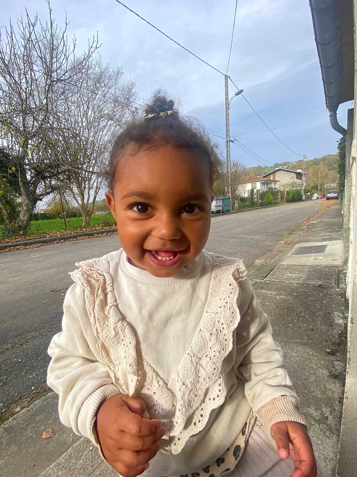 Liana participe au concours pour gagner de l'argent avec cette photo : toddler, child, smiling, outdoor, street, sweater, lace, happy, person, portrait, daylight, trees, sidewalk, curb, clothing, cute, young_child, face, eyes, hand