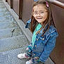 casual_clothing, child, colorful_pants, daylight, denim_jacket, fashion, girl, glasses, greenery, handrail, happy, metal_stairs, nature, outdoor, person, playful, portrait, smiling, sneakers, young