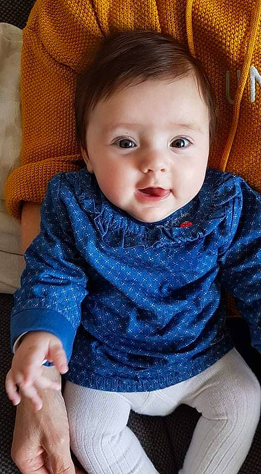 Lola participe au concours pour gagner de l'argent avec cette photo : arm, azure, baby_toddler_clothing, blue, cheek, eye, face, hand, human_body, joint, lip, mouth, neck, nose, organ, outerwear, person, skin, sleeve, standing