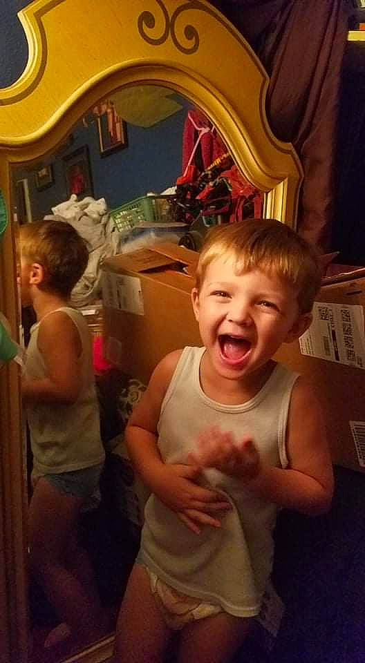 Karsen is registered to the contest to win money with this photo: arm, baby, child, event, flesh, fun, gesture, happy, human, mammal, mouth, organ, person, room, shorts, smile, standing, t_shirt, thumb, toddler