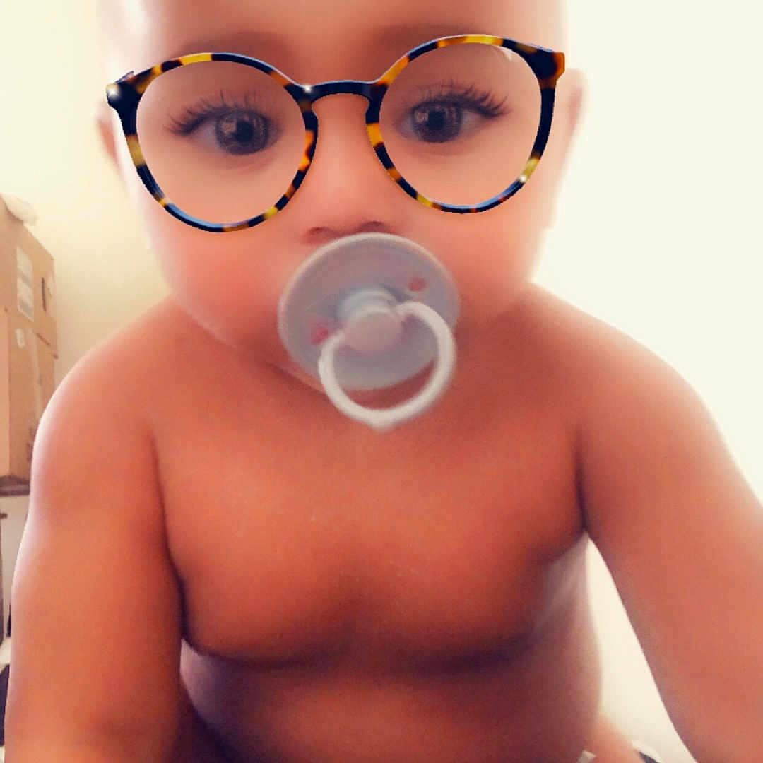 Kalaya Imagine Gray is registered to the contest to win money with this photo: baby, blurred_background, child, closeup, cute, cuteness, diaper, digital_filter, expression, eyes, face, glasses_filter, indoors, infant, pacifier, playful, portrait, sitting, skin, soft_light