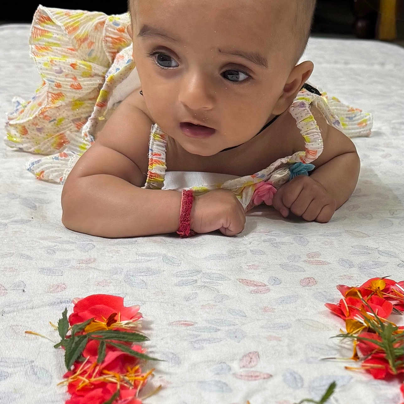 Takshvi joined the competition — help win amazing prizes! baby, bracelet, child, closeup, colorful, curious, cute, decorative, expression, eyes, face, flower_petals, head, heart_shape, indoors, infant, patterned_cloth, skin, small_hands, tummy_time