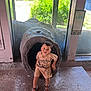 Shyloe joined the competition — help win amazing prizes! boy, casual_clothing, child, concrete_floor, curious, daylight, glass, greenery, indoor, log, nature, playful, portrait, sandals, shorts, smiling, standing, sunlight, tshirt, window