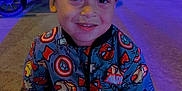Shyloe joined the competition — help win amazing prizes! blue_lighting, casual, child, clothing, face, happy, jacket, marvel, night, outdoor, person, portrait, purple_lighting, sidewalk, sitting, smiling, stroller, superhero, wheel, young