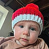 baby, child, face, hat, knitted_hat, red_hat, indoor, window, wooden_ceiling, curious, cute, person, portrait, clothing, closeup, eyebrows, skin, cheeks, hand, natural_light