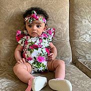 Maya participe au concours pour gagner de l'argent avec cette photo : baby, child, sitting, couch, floral, headband, romper, curly_hair, indoor, patterned_fabric, wide_eyes, pink, footwear, infant, expression, cute, person, furniture, skin, portrait