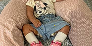 Maya participe au concours pour gagner de l'argent avec cette photo : baby, child, clothing, curious_expression, cushion, cute, denim_shorts, footwear, headband, indoor, infant, minnie_mouse, patterned_background, person, pink, seated, sneakers, socks, soft_furniture, tshirt