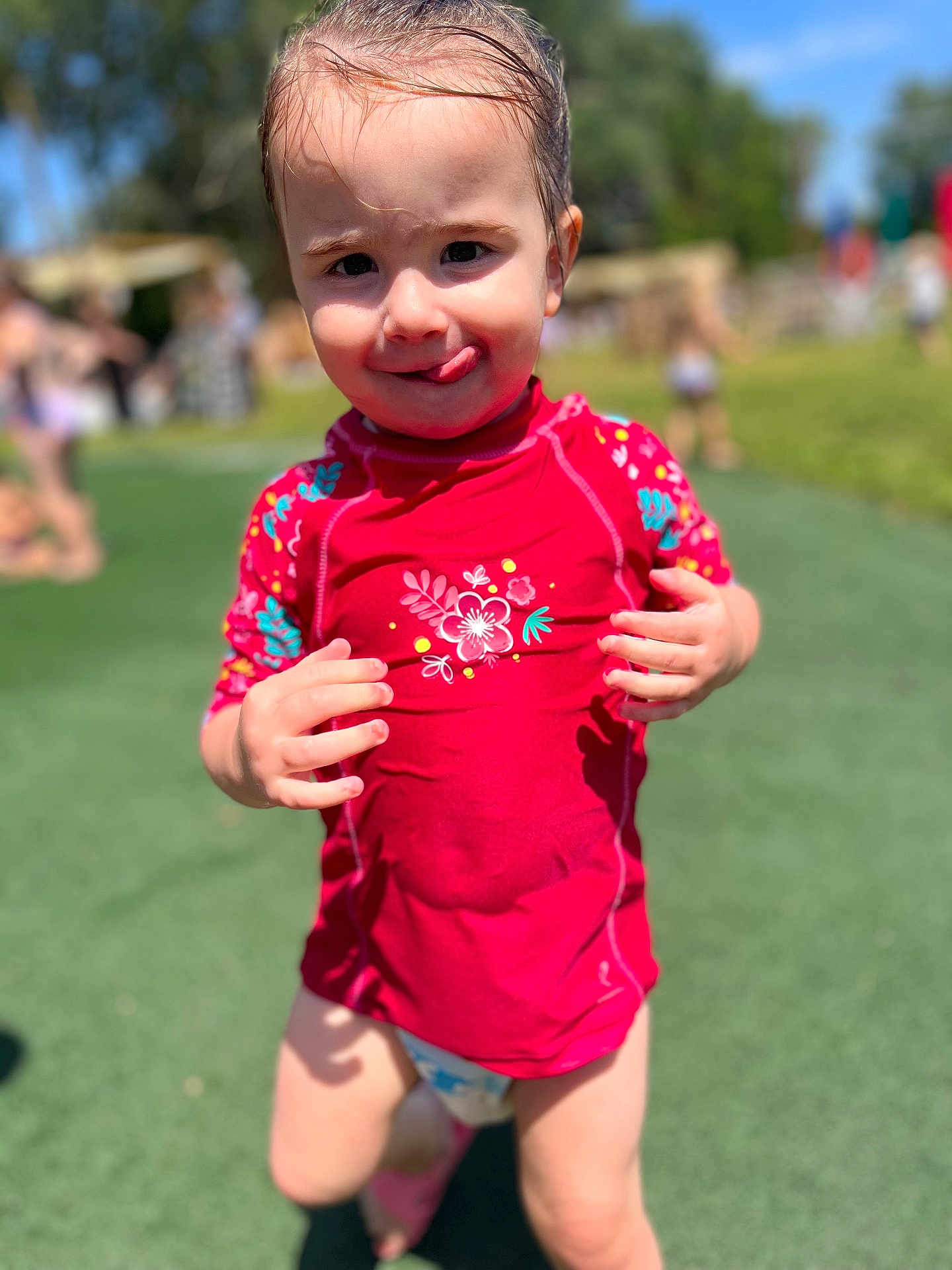 Inaya a rejoint le concours — aidez-le/la à gagner de superbes lots ! barefoot, child, cute, daylight, fun, grass, happy, outdoor, person, play, playground, red_shirt, smiling, summer, sunny, swimwear, toddler, tongue_out, water_play, young_child