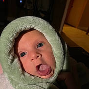 Weston joined the competition — help win amazing prizes! baby, infant, face, tongue, hood, towel, wrapped, skin, eyes, expression, closeup, indoors, dim_light, soft_texture, person, cute, newborn, head, playful, portrait