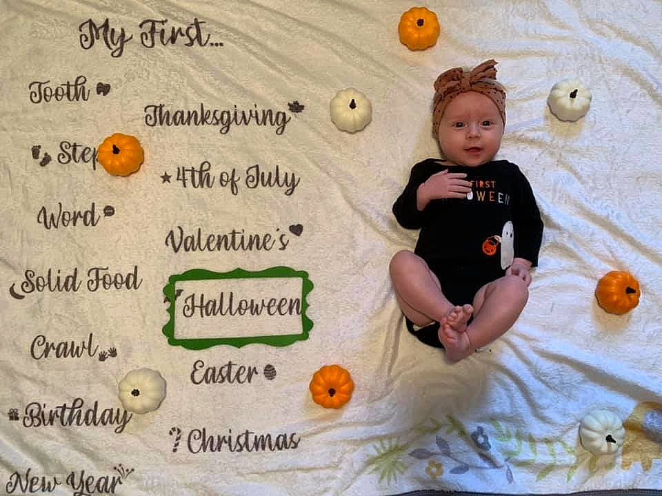 Hadley is registered to the contest to win money with this photo: baby, baby_toddler_clothing, calabaza, child, flooring, font, happy, headwear, linens, natural_foods, orange, organism, pattern, person, product, pumpkin, recipe, sitting, t_shirt, toddler