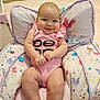 Alaina is registered to the contest to win money with this photo: baby, infant, child, pink_onesie, smiling, cushion, butterfly_pattern, indoor, toy_car, carpet, happy, chubby, seat, cute, person, skin, furniture, room, playroom, comfortable
