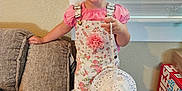 Juliette joined the competition — help win amazing prizes! child, girl, smiling, indoor, pigtails, pink_clothing, floral_overall, hat, socks, couch, window_blinds, wooden_bench, diaper_box, happy, person, portrait, home, furniture, cute, playful