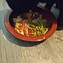 bowl, food, green_beans, chicken, wooden_floor, dog_paw, pet, blurry, indoor, meal, plate, tableware, animal, dark_shape, kitchen, flooring, close_up, dining, home, brown