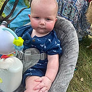 Rodney is registered to the contest to win money with this photo: baby, child, infant, outdoor, grass, seat, toy, blue_clothing, patterned_clothing, shark_pattern, serious_expression, cushioned_seat, hand, face, head, skin, summer, nature, playtime, closeup