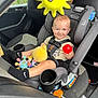 toddler, child, car_seat, toy, plush_toy, red_ball, car_interior, seatbelt, smile, clothing, sock, nike, window, door, cup_holder, graco, seat, person, sun_emoji, vehicle