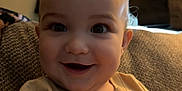 Leon is registered to the contest to win money with this photo: baby, smiling, child, face, eyes, shirt, tshirt, cartoon_character, simba, couch, furniture, indoors, portrait, happy, person, young_child, cozy, warm_lighting, texture, seated