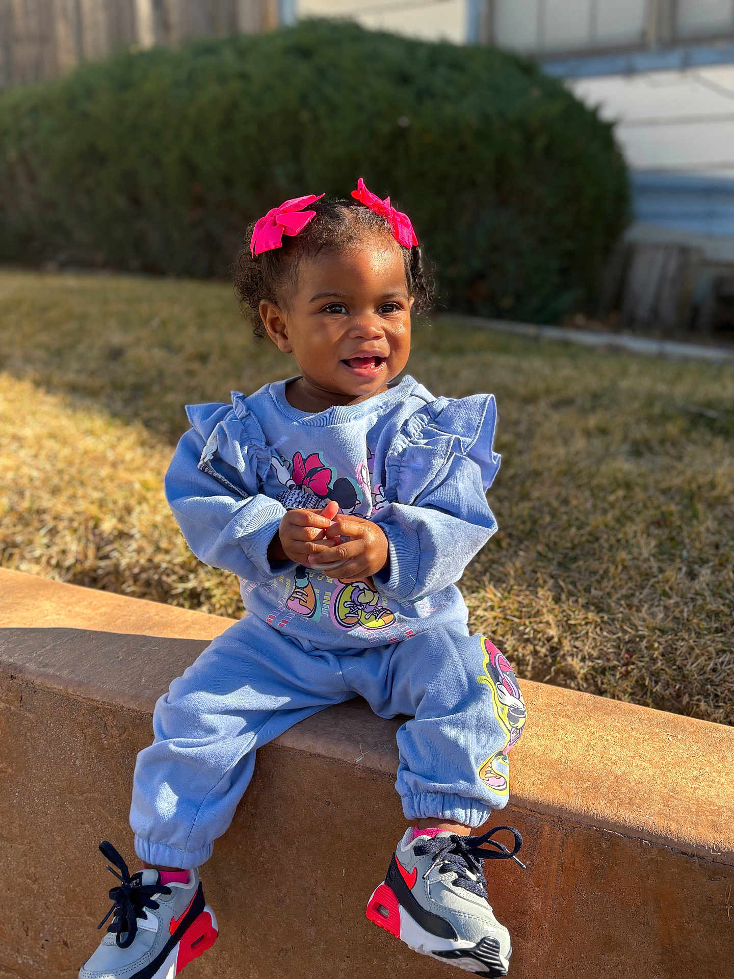 Londyn joined the competition — help win amazing prizes! blue_outfit, bows, cartoon_print, casual_clothing, child, cute, daytime, grass, hair_accessories, happy, outdoor, person, shoes, sitting, smiling, sneakers, stone_ledge, sunlight, toddler, young_child