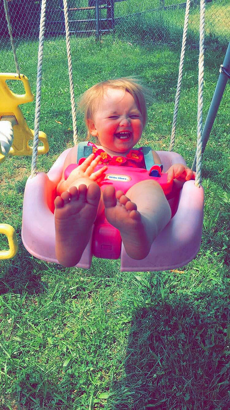 Alison is registered to the contest to win money with this photo: baby, child, fun, grass, joy, leg, outdoor_play_equipment, person, play, smile, summer, swing, toddler, vacation