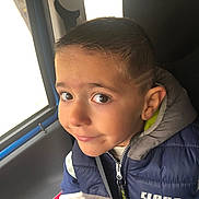Djulian a rejoint le concours — aidez-le/la à gagner de superbes lots ! child, boy, portrait, smile, jacket, car_seat, vehicle, window, hairstyle, zipper, clothing, face, expression, indoor, casual, warm_clothing, seatbelt, young_child, person, light