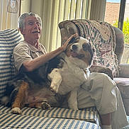 Bjneville joined the competition — help win amazing prizes! armchair, carpet, casual_clothing, companion, couch, dog, elderly_man, footwear, hand_pet, happy, home_interior, indoor, natural_light, pet, seated, smiling, striped_couch, sunlight, vertical_blinds, window