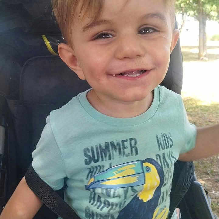 Ayden participe au concours pour gagner de l'argent avec cette photo : casual_clothing, child, cute, daytime, greenery, happy, nature, outdoor, park, person, portrait, seatbelt, shorts, smiling, stroller, summer, sunlight, toddler, tree, young