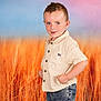 child, boy, portrait, standing, hands_on_hips, shorts, shirt, denim, casual_clothing, blue_eyes, short_hair, smiling, background, grass, outdoor_style, colorful_background, studio_photo, confident, young, cute