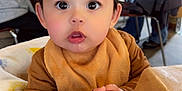 River is registered to the contest to win money with this photo: baby, child, blanket, high_chair, cafe, indoor, people, table, chair, face, hands, expression, clothing, person, drinks, blurred_background, curious, cute, warm_colors, family