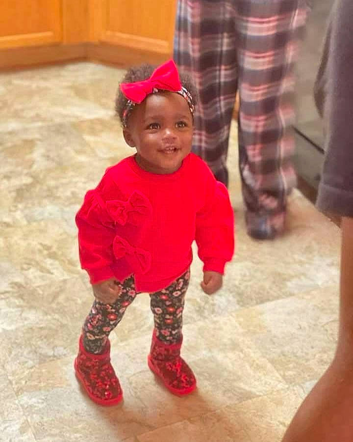 Blessings is registered to the contest to win money with this photo: baby, baby_toddler_clothing, christmas, event, floor, flooring, fun, happy, head, headwear, human_leg, joy, leg, outerwear, pattern, person, sleeve, smile, sock, tartan