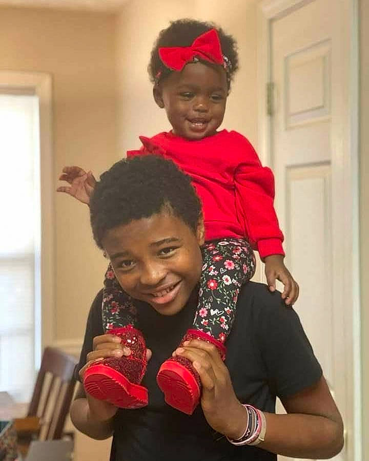 Blessings is registered to the contest to win money with this photo: child, community, door, elbow, event, fashion, fashion_design, fun, gesture, hairstyle, happy, interaction, joy, mammal, person, red, sleeve, smile, standing, t_shirt