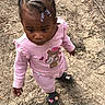 toddler, child, baby, outdoors, standing, portrait, face, braids, beads, pink_clothing, striped_pants, shoes, teddy_bear, cartoon, curious, looking_up, dirt, ground, natural_light, full_body