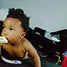 Alaia joined the competition — help win amazing prizes! baby, child, infant, portrait, indoors, bedroom, sitting, curious, looking_away, bottle, feeding, bare_chested, earring, curly_hair, dark_skin, bed, blanket, clothing, toys, home