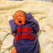 Makaio is registered to the contest to win money with this photo: baby, newborn, infant, sleeping, yawning, blanket, clothing, onesie, purple, red_text, cute, toddler, indoors, soft, cozy, person, child, human, small, resting