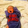 baby, newborn, infant, sleeping, yawning, blanket, clothing, onesie, purple, red_text, cute, toddler, indoors, soft, cozy, person, child, human, small, resting