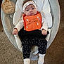 baby, infant, halloween, bib, headband, baby_seat, carpet, clothing, socks, black_pants, white_shirt, orange_bib, wooden_sign, indoor, cute, looking_at_camera, soft_texture, festive, holiday, child