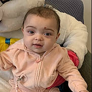 Khloe is registered to the contest to win money with this photo: baby, baby_girl, casual_clothing, child, comfortable, cute, face, home, indoor, infant, phone_screen, pink_clothing, plush_toy, portrait, relaxed, sitting, smiling, soft_toy, time_display, young_child