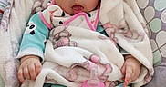 Khloe is registered to the contest to win money with this photo: baby, baby_seat, blanket, bottle, child, clothing, comfort, cushion, cute, face, hand, indoors, infant, milk, onesie, panda_print, person, portrait, soft_toy_pattern, wide_eyes