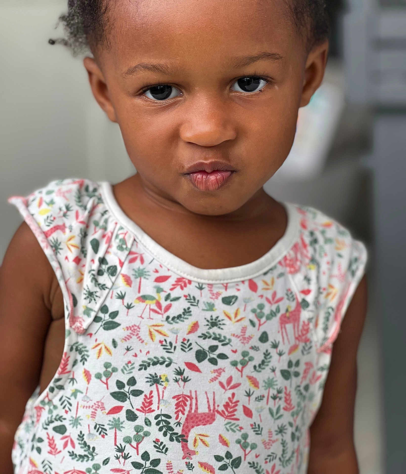 Edene a rejoint le concours — aidez-le/la à gagner de superbes lots ! child, toddler, face, portrait, expression, pout, clothing, patterned_shirt, colorful, sleeveless, cute, indoor, skin, hair, eyes, person, young, closeup, funny_face, background_blur