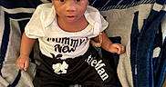 Jeremiah joined the competition — help win amazing prizes! baby, black_pants, blanket, child, clothing, cute, eyes, face, foot, hand, hat, indoors, infant, mouth, patterned_blanket, person, portrait, sitting, socks, white_shirt