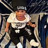 baby, black_pants, blanket, child, clothing, cute, eyes, face, foot, hand, hat, indoors, infant, mouth, patterned_blanket, person, portrait, sitting, socks, white_shirt