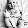 baby, smile, onesie, plush_toy, blanket, socks, infant, face, happy, cute, child, portrait, black_and_white, soft_toy, sitting, fabric, cozy, indoor, young_child, cuddly